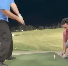 Man swings golf club at night