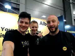 Three men posing for a selfie at a convention