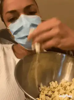 Woman eating popcorn with face mask