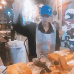 Man in blue hat dancing behind counter