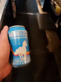 Hand holding blue Montucky Cold Snack can