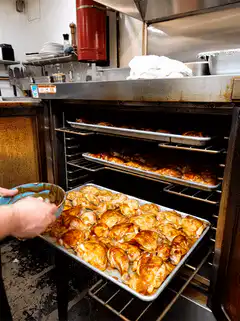 Chef basting chicken in oven