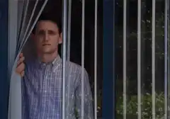 Man peering through blinds