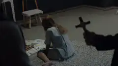 Girl drawing while cross is held up