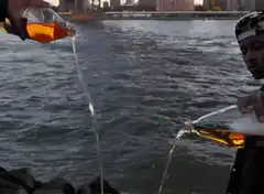 Two men pouring beer into the river