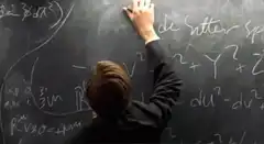 man writing complex math on chalkboard