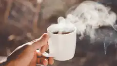 hand holding steaming coffee mug outdoors