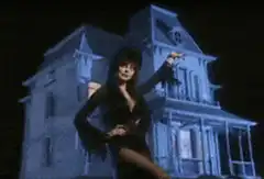 Morticia Addams posing in front of the Addams Family mansion