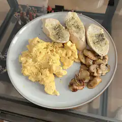 plate of scrambled eggs, mushrooms, and garlic bread