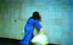 Woman in blue dress hits wall with bag
