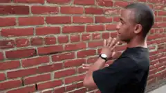 Man doing martial arts moves against brick wall