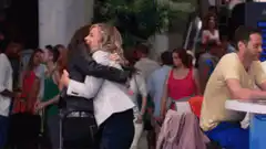 Penny hugs Amy while Sheldon watches
