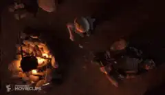 Two men sitting by a campfire at night