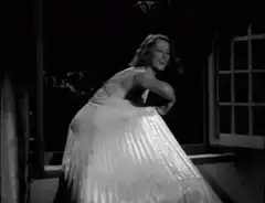Woman in white dress dancing by window