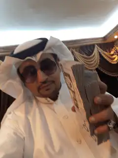 Man in thobe showing stacks of cash