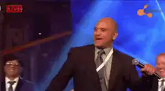 Bald man dancing on stage with microphone