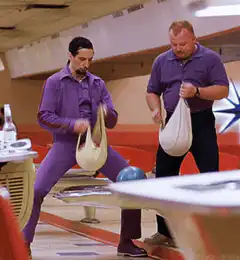 Two men in purple holding bowling bags
