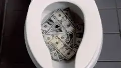 Toilet full of money being flushed