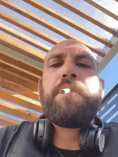 bearded man smoking under pergola