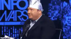 Alex Jones wearing tinfoil hat smirking