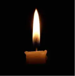 Single candle flame in darkness
