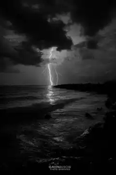 lightning strikes over ocean at night