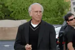 Larry David walking and grimacing
