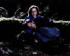 Woman holding man in forest saying Ow