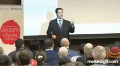 Man in suit gesturing on stage at conference