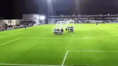 People carrying a soccer goal across the field