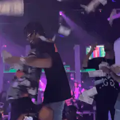 People dancing in a club with money flying