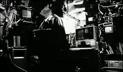 Man in cluttered room with monitors