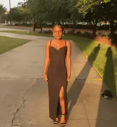 Woman in black dress posing on sidewalk