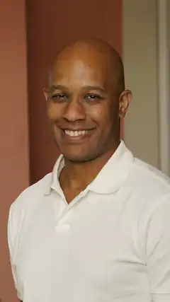Bald man in white polo smiling