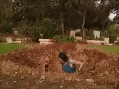 woman digging in a grave with beer