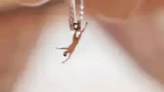 Tiny doll falling from tweezers