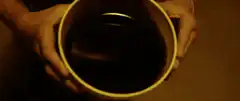 Hands holding a cup of dark liquid