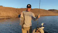 Man holding up a large bass on a boat