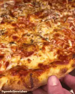 Hand pulling cheesy pizza slice