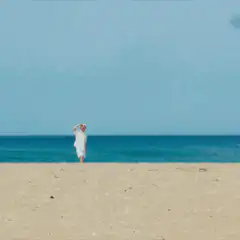 man in white on beach shielding eyes