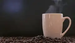 steaming coffee mug on beans