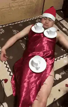 Man in red dress with teacups and Merry Christmas sign