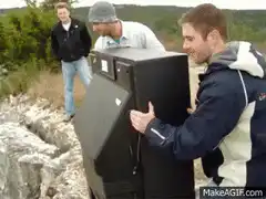 men throwing old tv off cliff