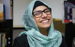 Woman in hijab and glasses smiling broadly