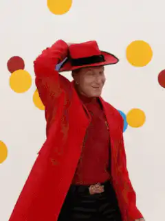 Man in red suit tips hat