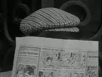 Man in cap and sunglasses reading newspaper