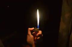 hand holding a lit lighter in the dark