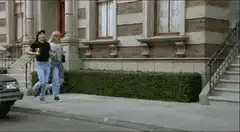 Two women walking past two men on a sidewalk