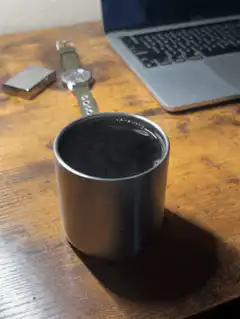 Steaming metal cup on wooden desk