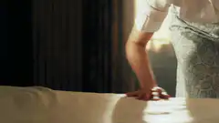 maid smoothing bed sheets